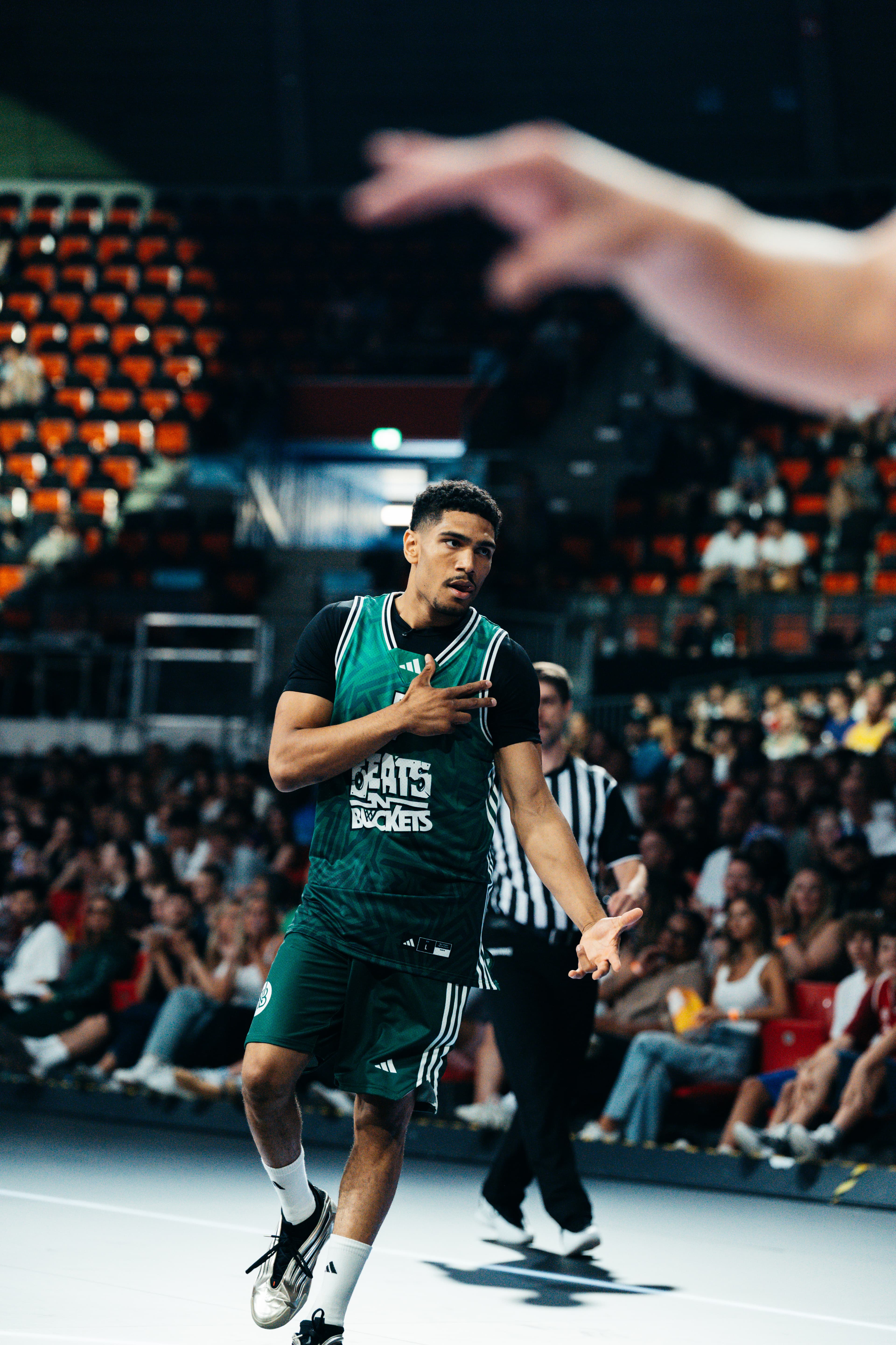 Spieler im grünen Beats-N-Buckets-Trikot mit Hand auf der Brust vor roten Rängen