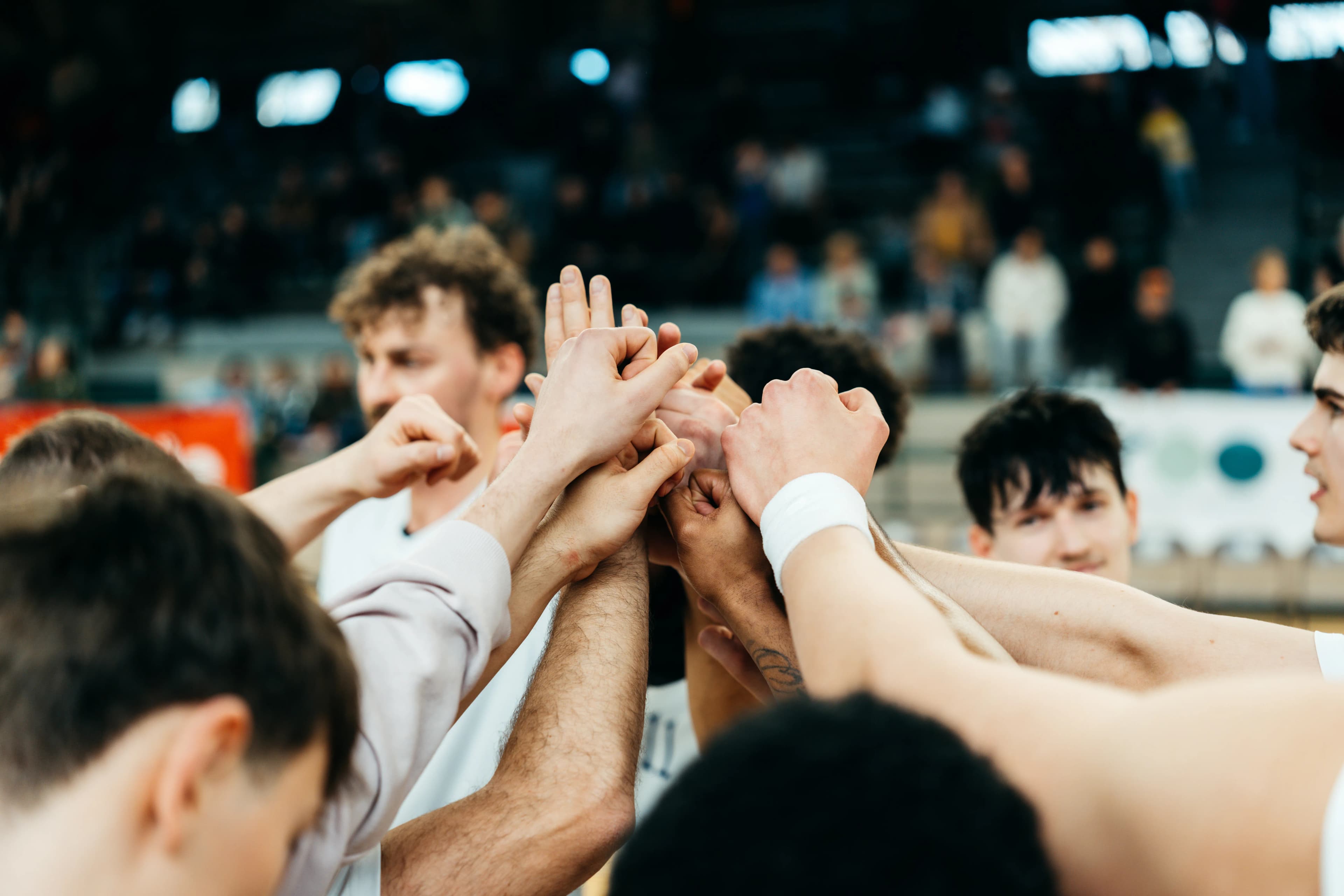 Berlin Dreams team huddle with hands stacked together in front of the stands