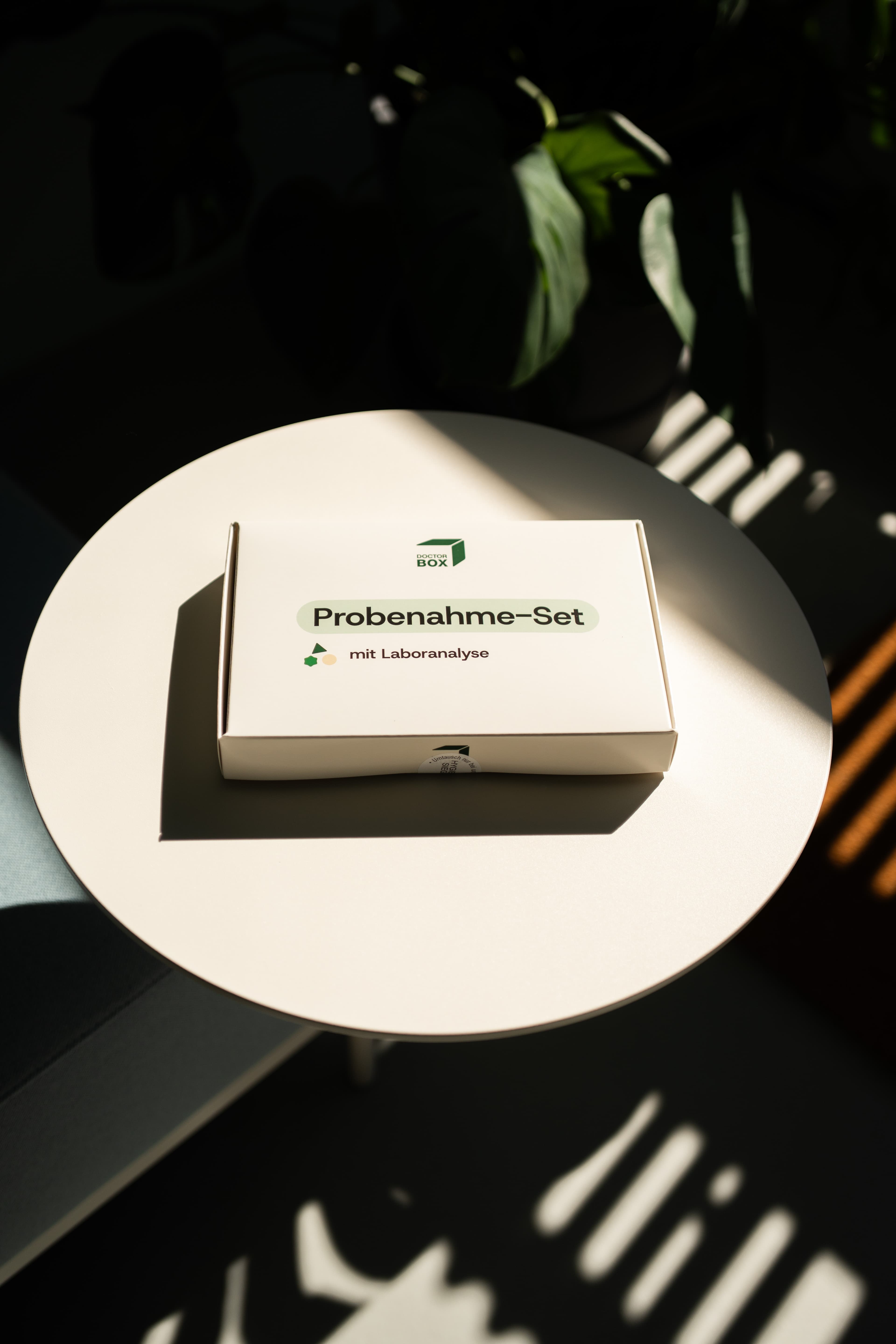 DoctorBox Probenahme-Set auf Beistelltisch im Gegenlicht — Heimtest mit Laboranalyse