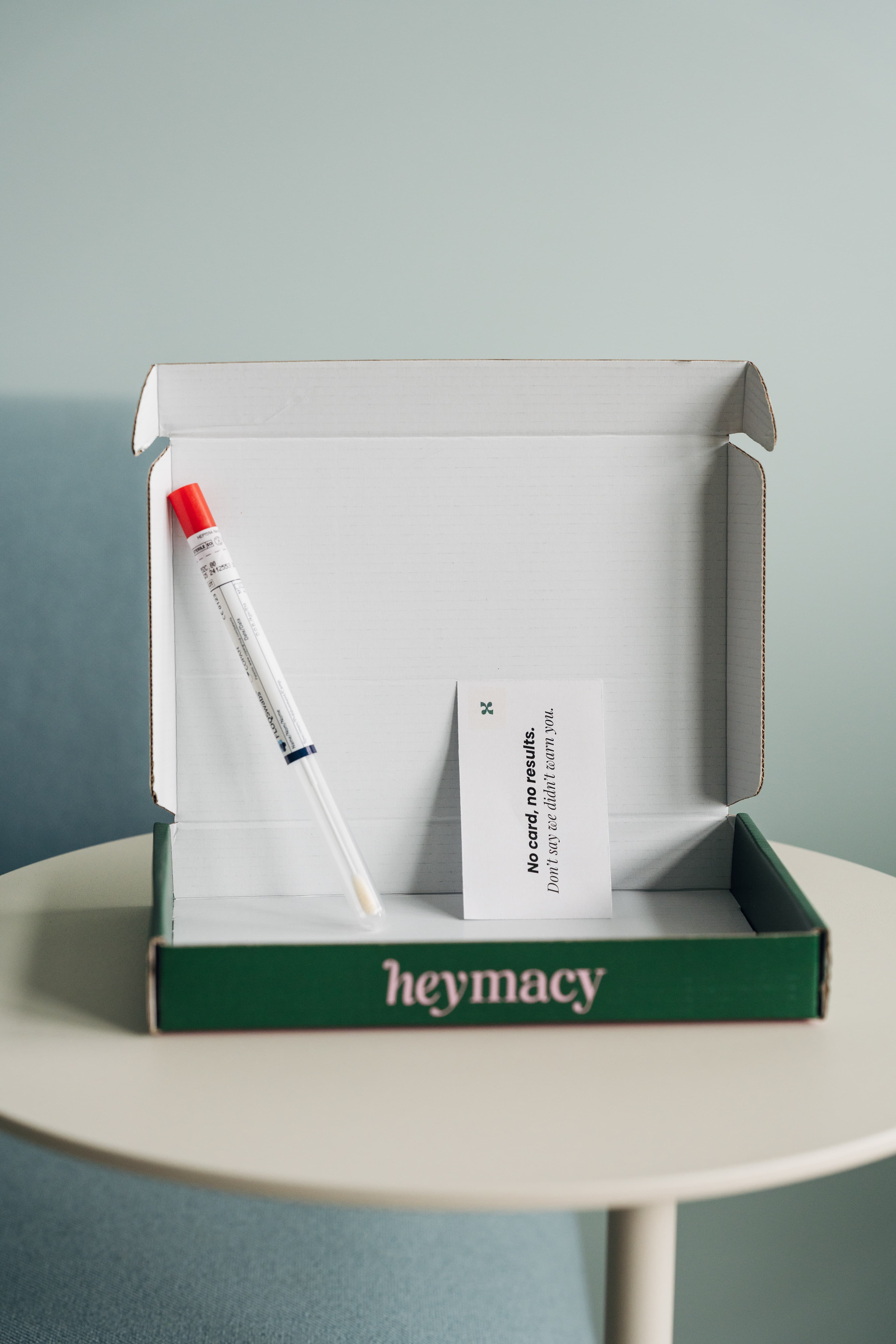 Open heymacy box with a swab tube, red cap and warning card on the table