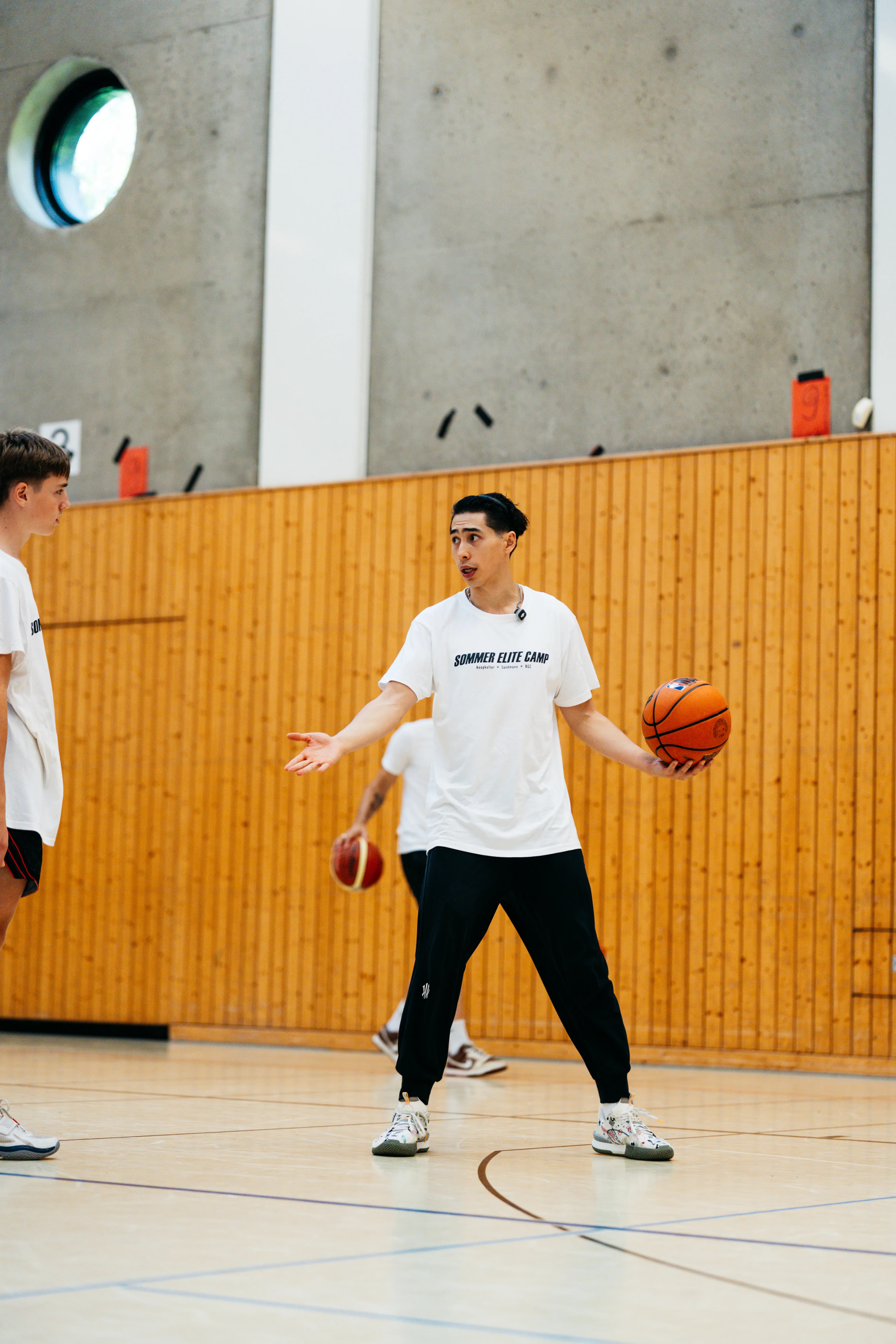 Coach in Sommer Elite Camp shirt holding a basketball and explaining the next drill